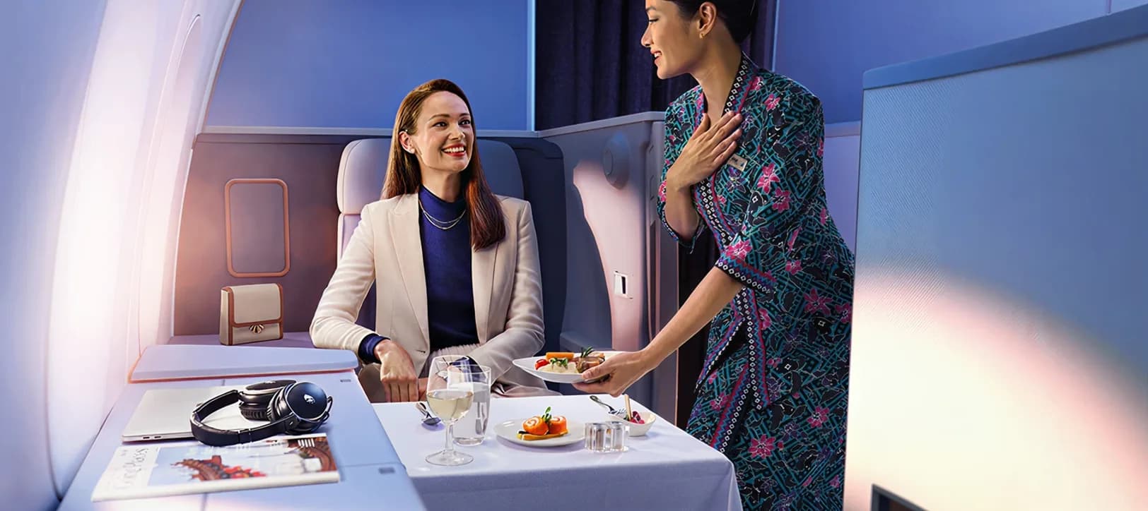 Cabin crew serving a passenger in a business class suite