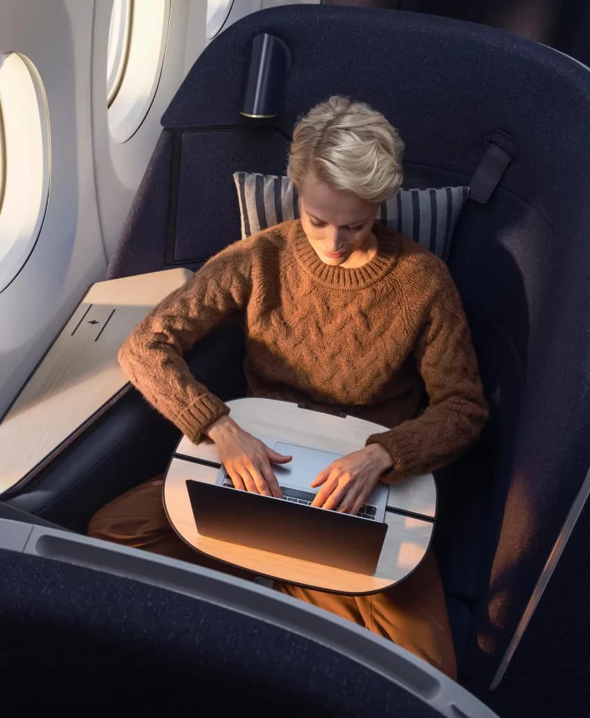 Woman working on a laptop in a business class seat